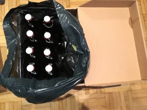 Acht Flaschen im dunklen Beutel in einer Kiste